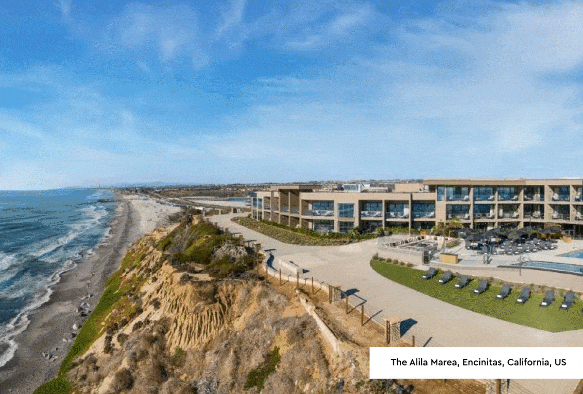Photo 1: Devon: Photograph of a coastal hotel complex situated on a grassy cliff overlooking a rocky beach and ocean. The scene features multiple white buildings with a Union Jack flag, outdoor seating areas, and a small pool, highlighting a serene seaside retreat. Photo 2: Encinitas, California: Photograph of a coastal resort featuring a modern building with large glass windows, an outdoor pool, and sun loungers arranged on a green lawn. The scene includes a sandy beach stretching along a rugged cliffside under a partly cloudy blue sky, highlighting a tranquil seaside atmosphere.