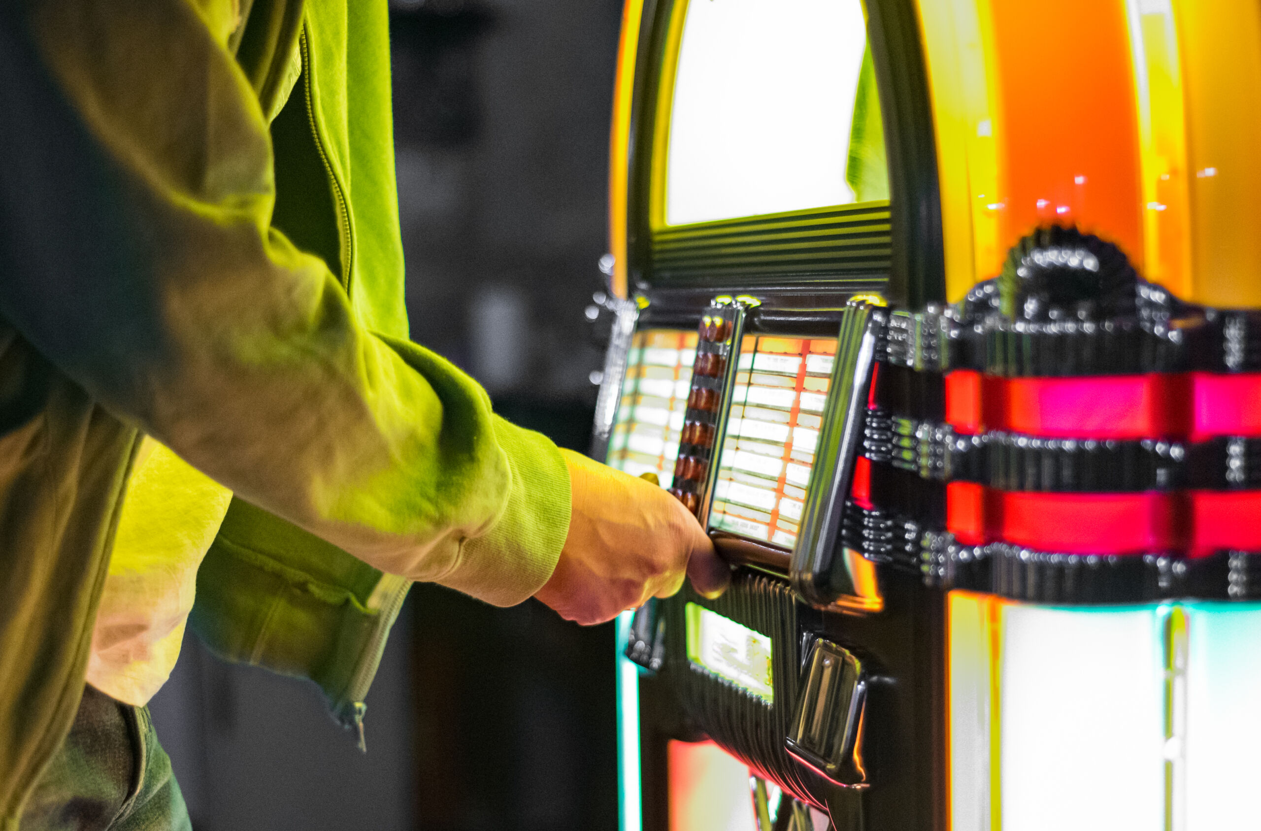Male hand pushing buttons to play song on old Jukebox, selecting records