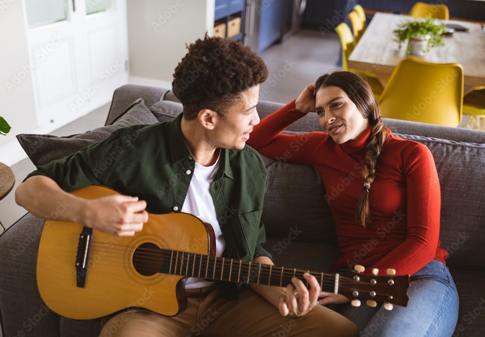 Couple sat on sofa, celebrating Valentine's Day with a guitar